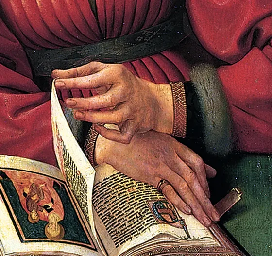A hand turning the page of an illuminated book